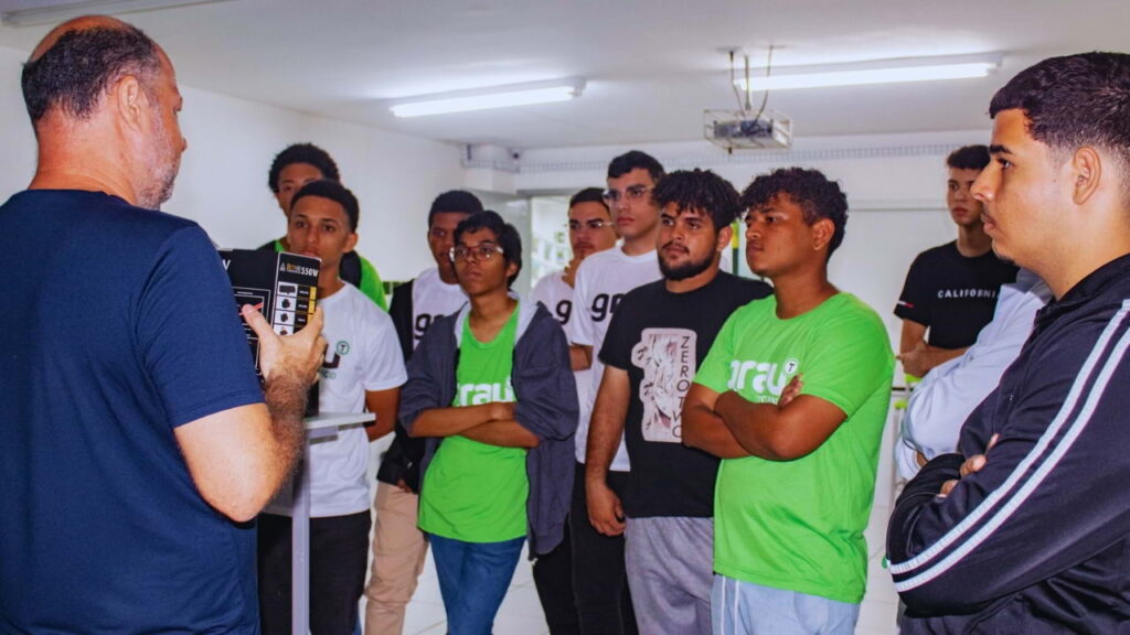 Grupo de alunos jovens assiste atentamente a uma apresentação prática em sala de aula do Grau Educacional.