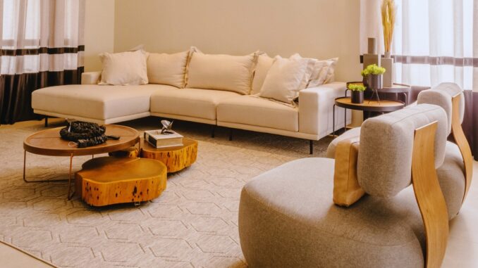 Sala de estar moderna com sofá bege e mesas de centro em madeira clara, sob luz natural