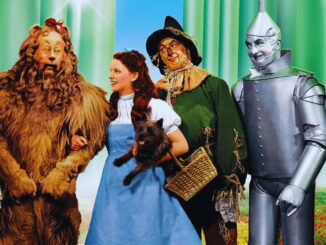 Cena do filme The Wizard of Oz (1939) mostrando Dorothy, o Espantalho, o Homem de Lata e o Leão Covarde em cores vibrantes do Technicolor.